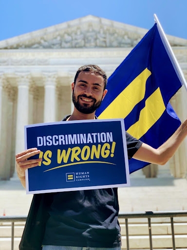 Students stands in front of supreme court with sign that says "discrimination is wrong" 