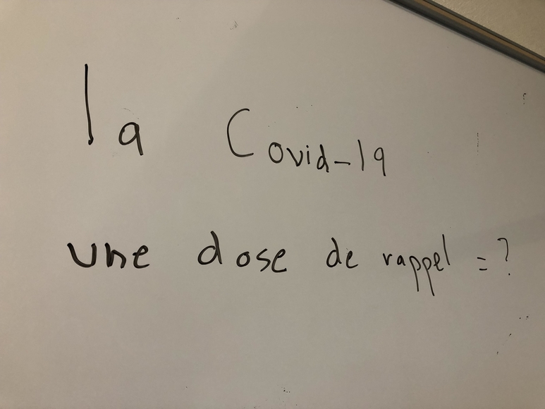 "la covid-19 une dose de rappel = ?" written on a whiteboard