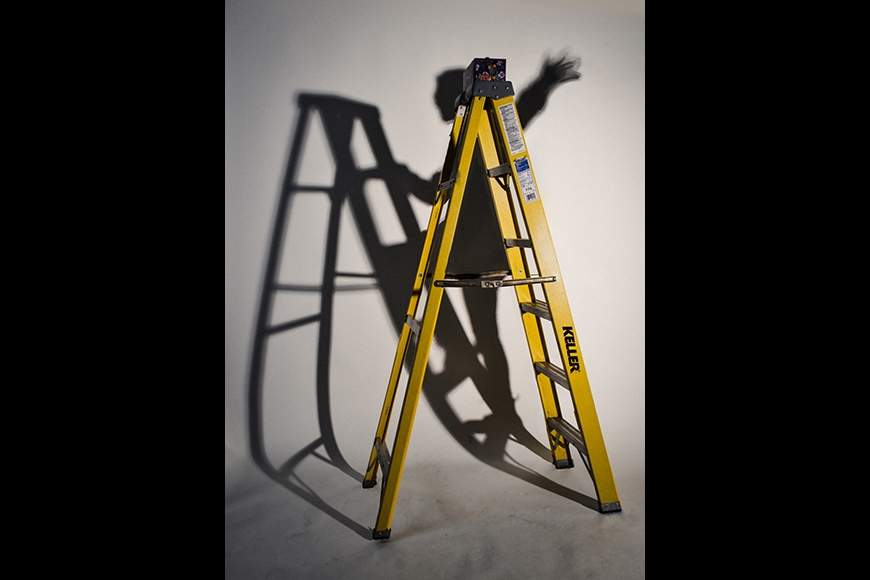 A yellow utility ladder casts a shadow of a figure climbing the ladder against a white background.