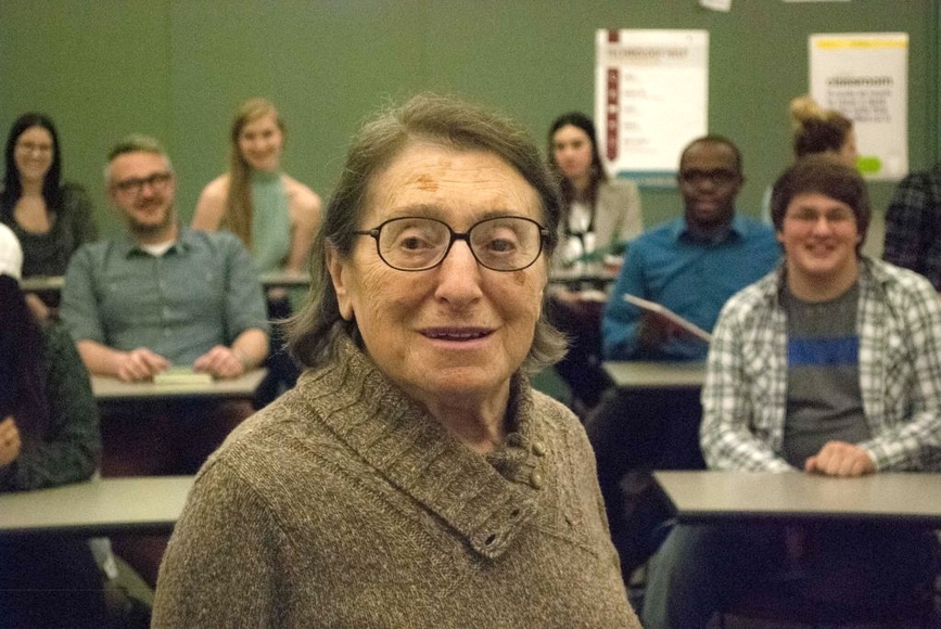 Dora Zidenweber looking at the camera with people seated in a classroom behind her