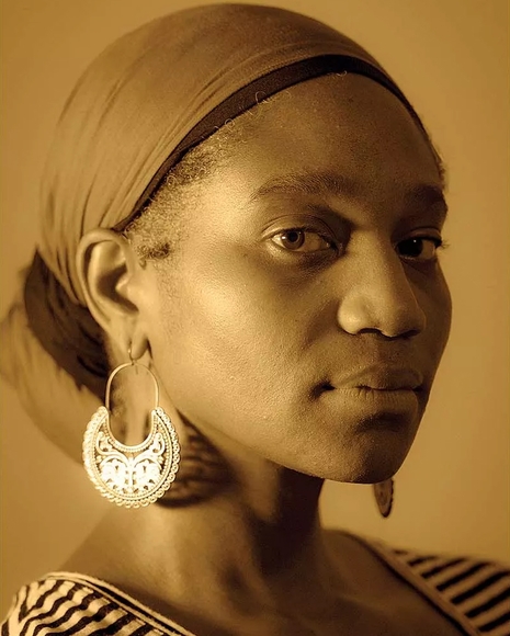 Sepia-toned headshot of Black woman wearing headscarf and earrings