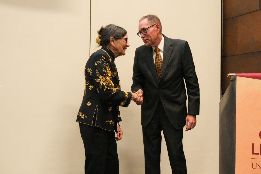 Dean Coleman shakes the hand of alumni awardee Sandra Larson