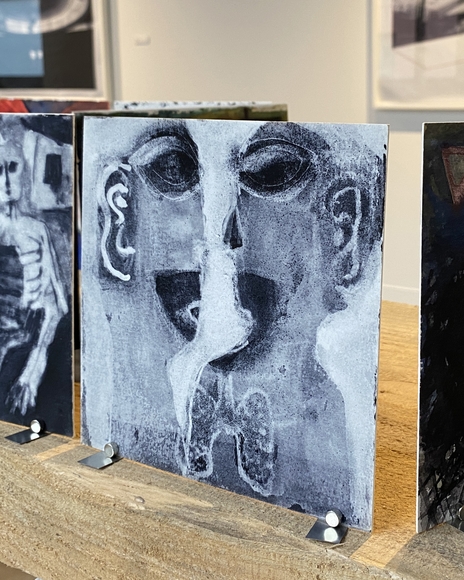 Stylized drawing of faces on a small card in an art gallery