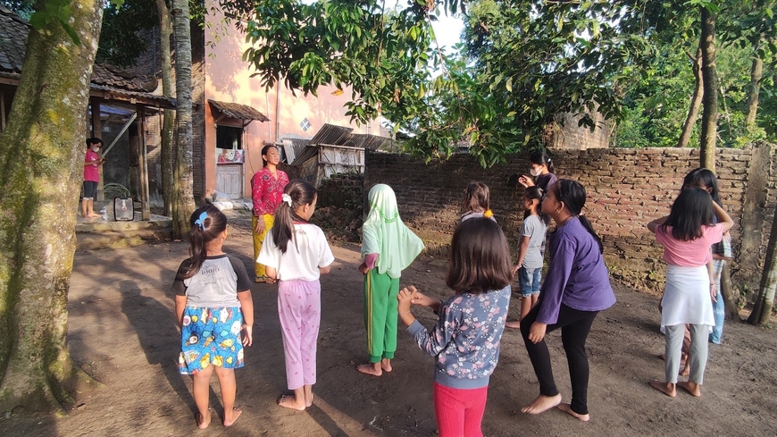 Diyah Larasati standing in front of a group of small children 
