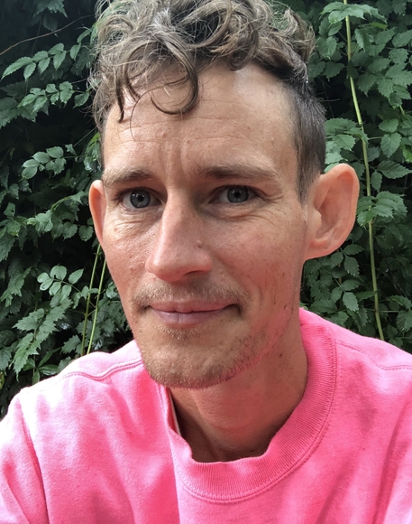 Photo of Emmett Ramstad wearing a pink t-shirt and looking into the camera