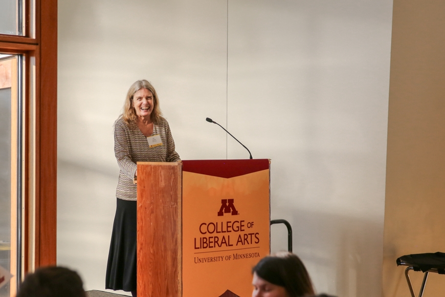 Interim Dean Ann Waltner smiles behind the podium as she delivers her remarks