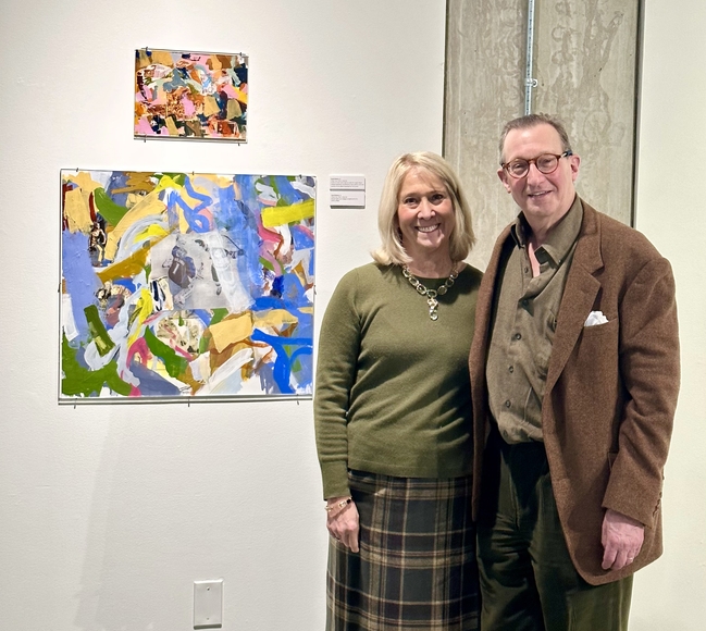A middle-aged couple stand next to brightly colored abstract art