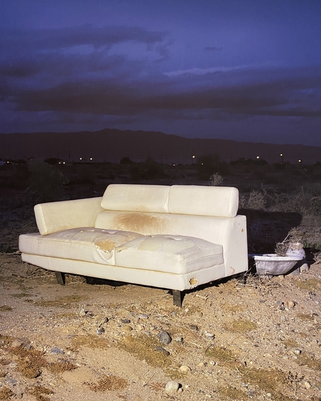 Soiled couch on the dirty ground at dusk