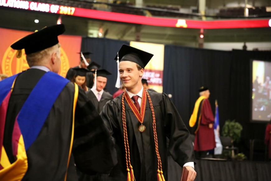 Henry Zurn shakes a man's hand at a graduation ceremony.