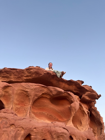 Bridget sitting on red rocks at Wadi Rum in Jordan.