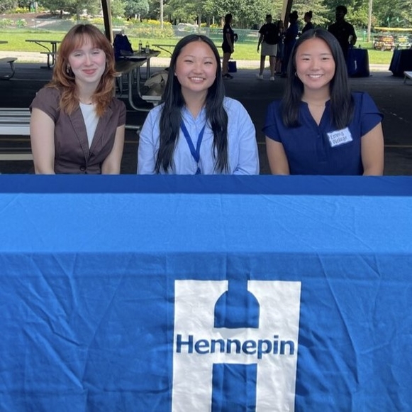 Makena and two other interns sitting at a table with a Hennepin County table cloth.