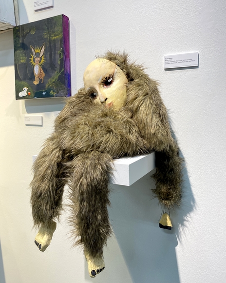 A stuffed animal sitting slumped on a pedestal wearing a blank human mask