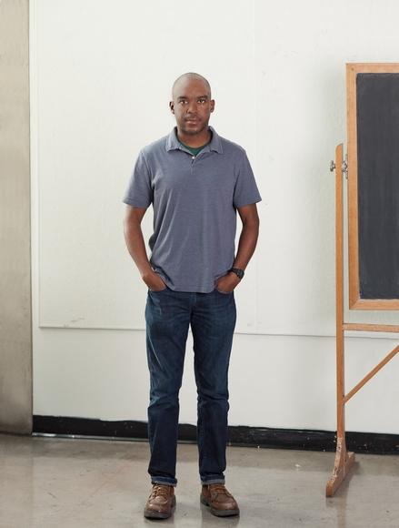 Associate Professor Lamar Peterson stands next to a chalkboard