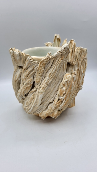 Ceramic vessel with an abstract, organic surface resembling dried corn husks.