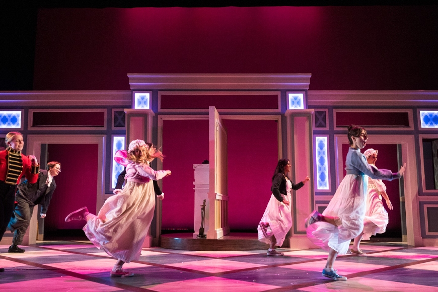 The cast dances in two lines, all facing to their left, with Lydia and Jane at the front, in red lighting.