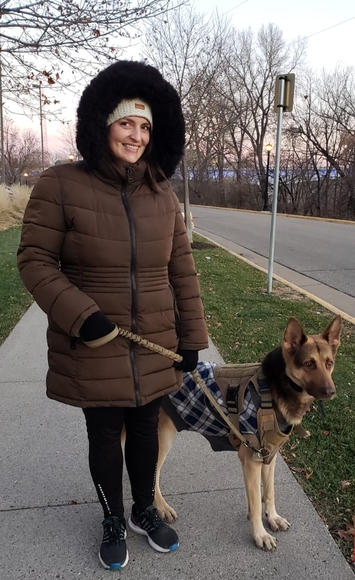 photo of woman in parka with black hood and german Shepard on leash