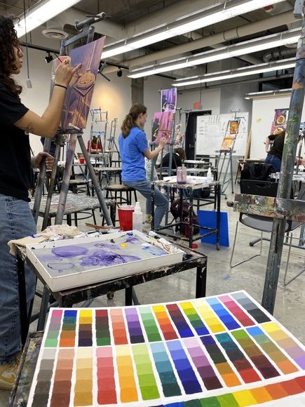 Color reference chart next to students painting on easels