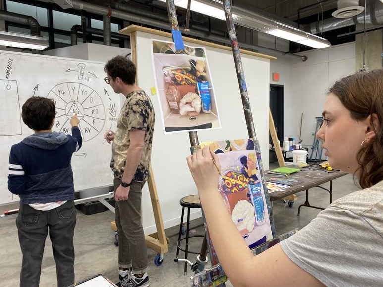 Students painting and studying a color wheel in an art studio