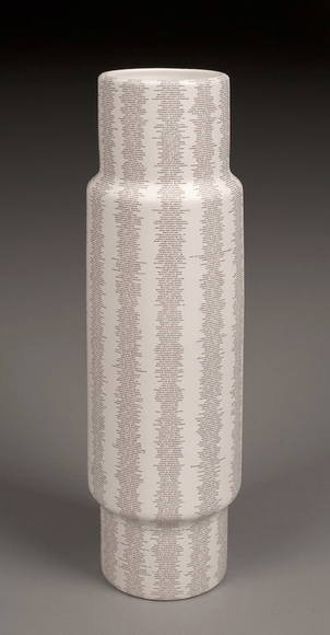 A white cylindrical vase tapered slightly at the top and bottom, printed with a list of the names of those killed in the terrorist attacks on 9/11/2001.