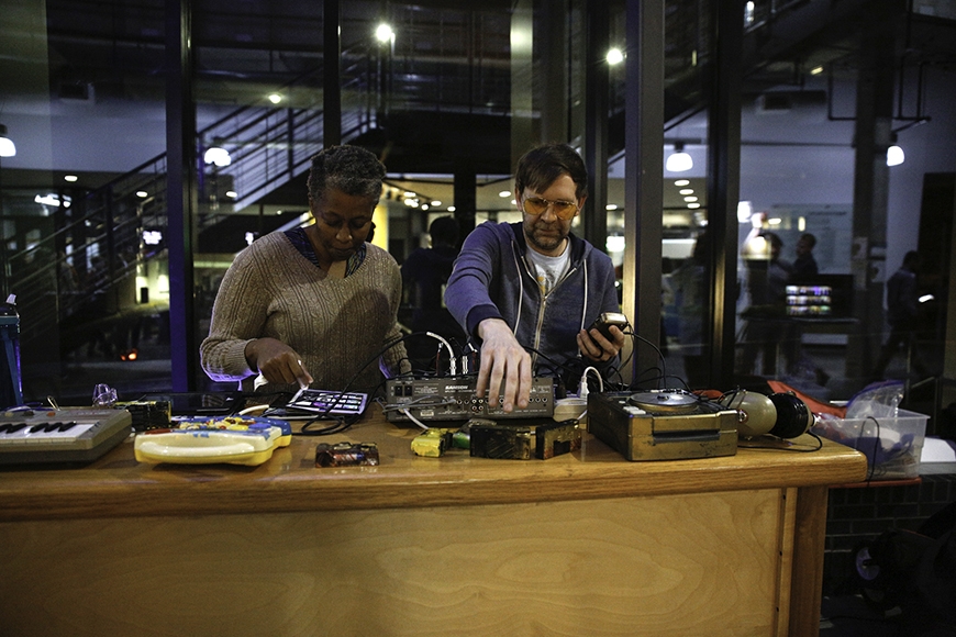 Two musicians making music from electronic devices at an interactive station called Audio Playground.