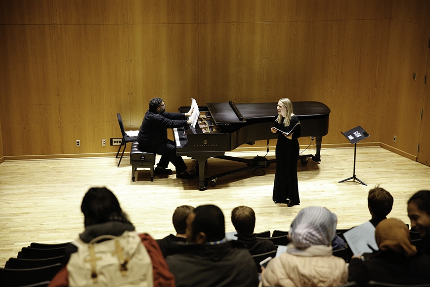 Student plays piano while another student sings on stage in the Ultan Recital Hall at Ferguson Hall.