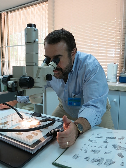 Bernie Levinson examines fragments of the Dead Sea Scrolls through a microscope.