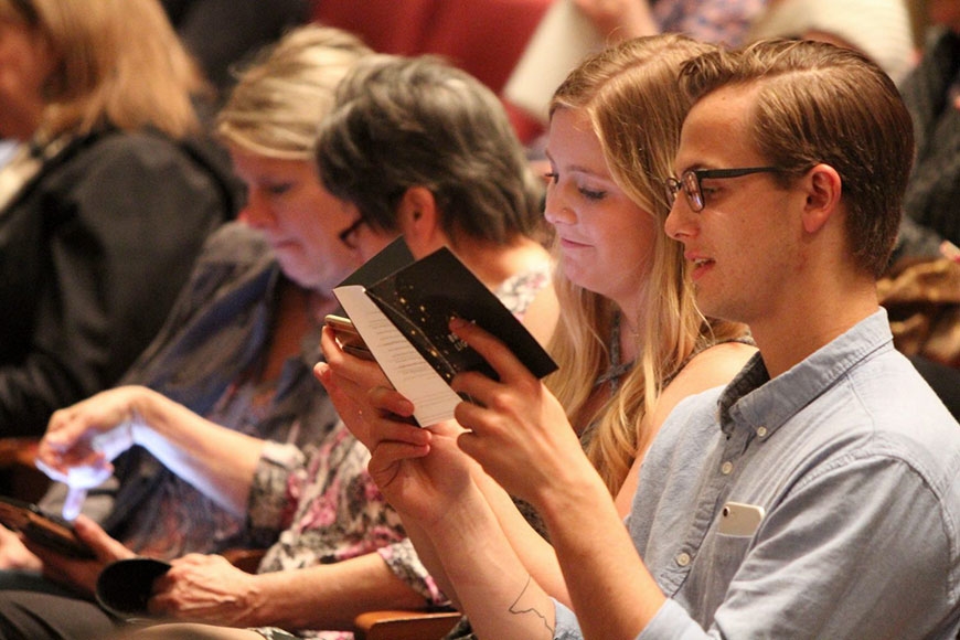 Photo of people in the audience reading the Bright Lights program
