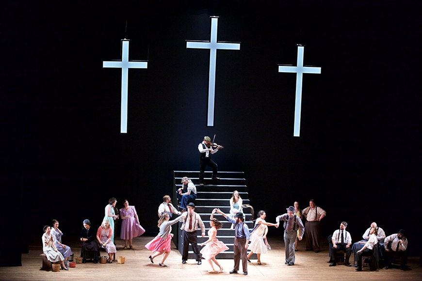 People dancing on stage with a cross in the background