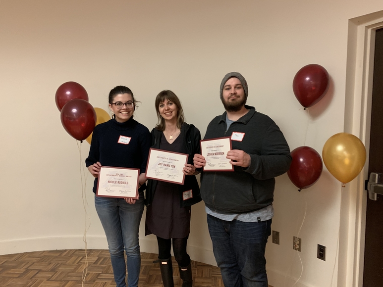 Nicole Rudisill, Joy Hamilton, Joshua Morrison hold up certificates in front of maroon and gold balloons