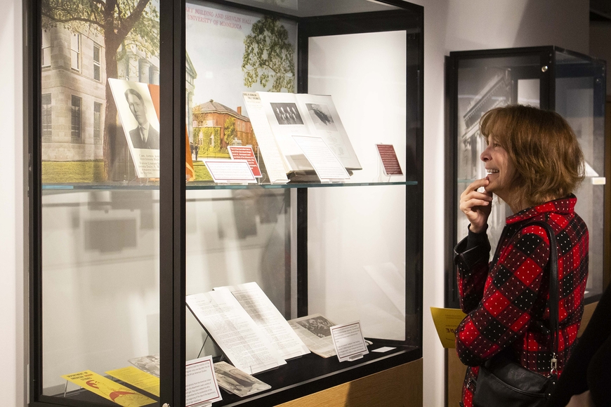 Woman smiling while looking at part of Calling to Question exhibit