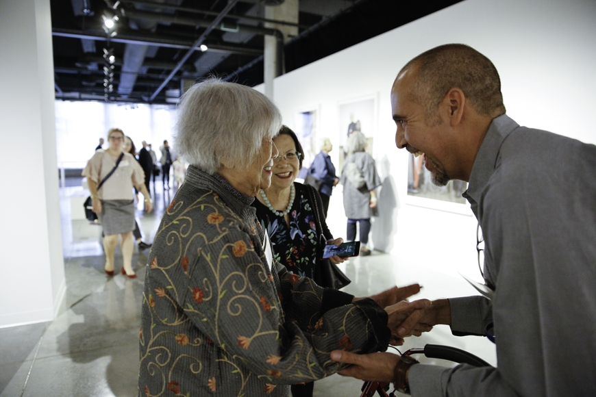 Woman featured in exhibit photo shaking hands with exhibit photographer, Xavier Tavera