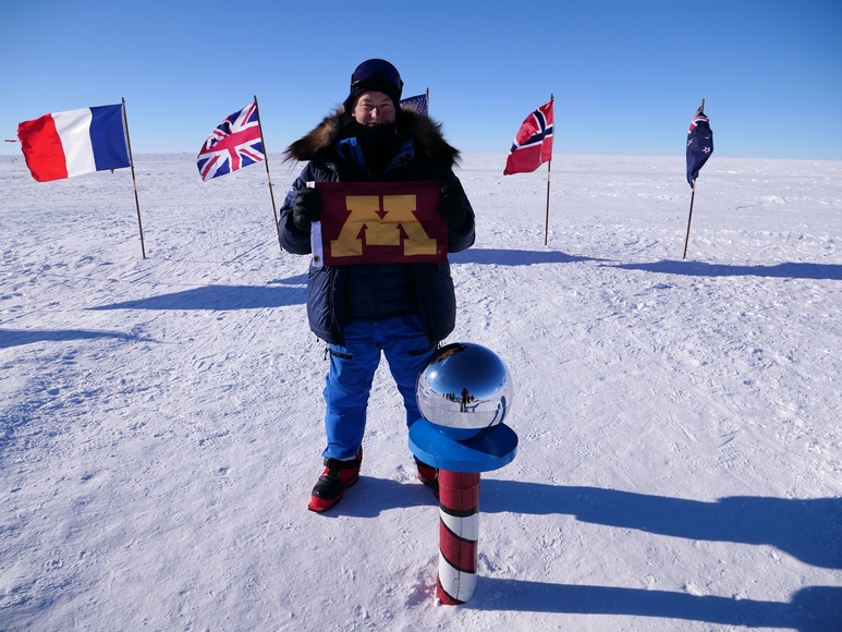 robert miller holding UofM flag at the South Pole