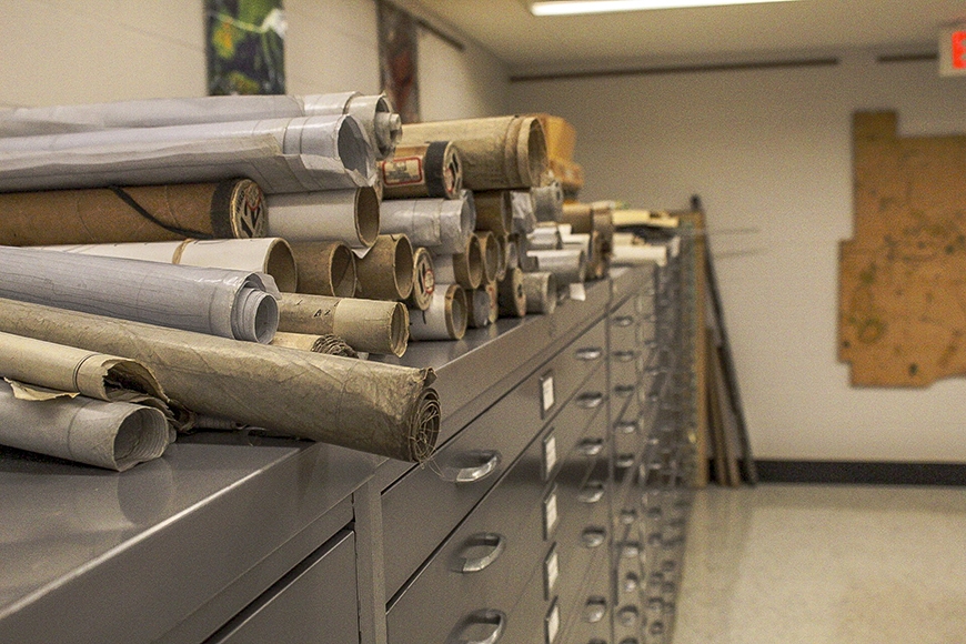Many rolled-up maps on top of a long filing cabinet