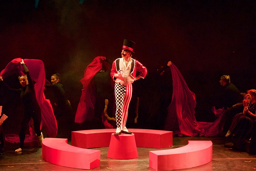 Ringleader man on a red bucket with several people dancing around him