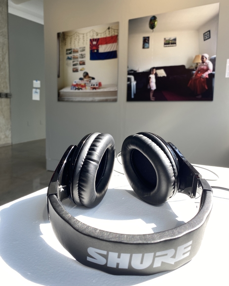 Black headphones sit on a pedestal in front of photos