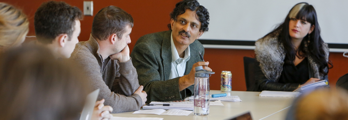 Professor Vinay Gidwani speaking with a group of students seated at a conference table