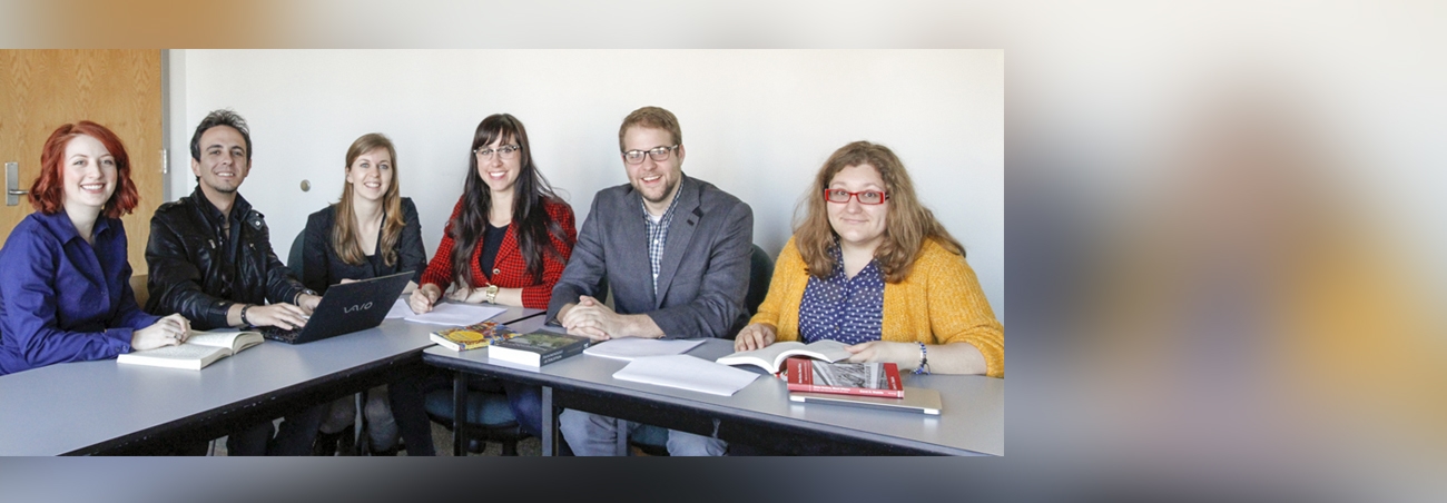Six communication studies grad students sitting around a desk