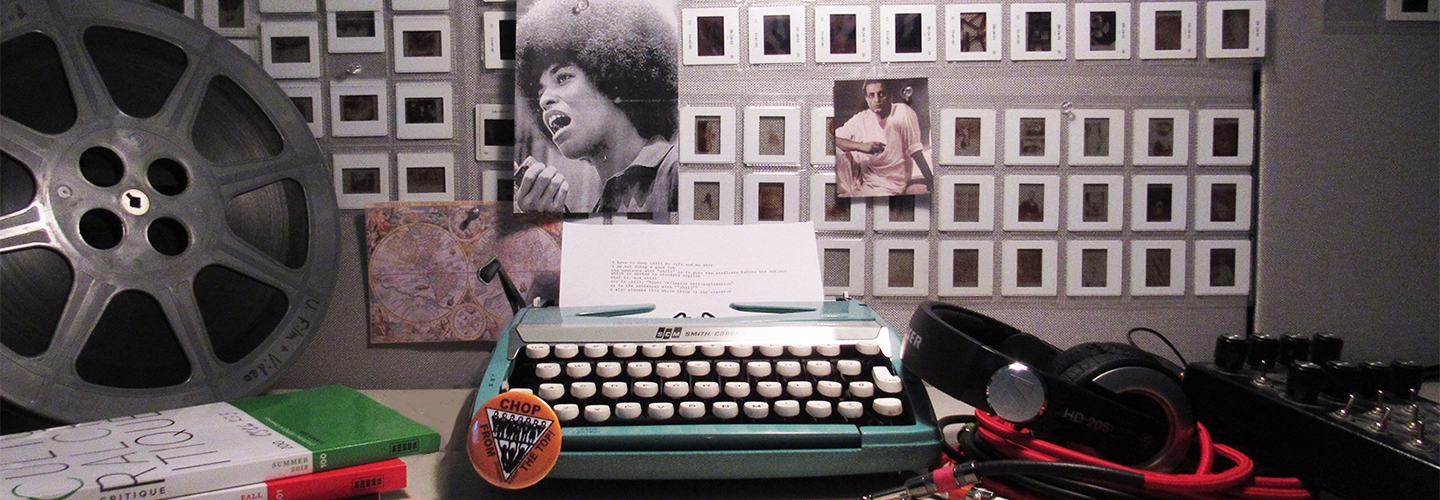 Various contemporary cultural artifacts, film reel, manual typewriter, photo of Angela Davis, rows of slides pinned to wall