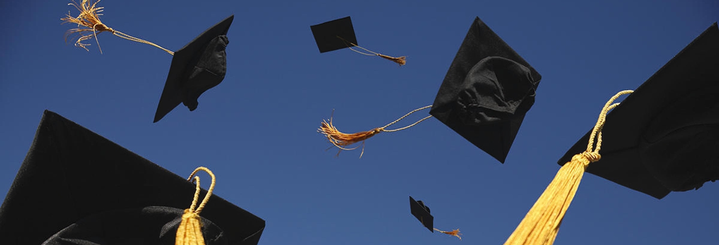 Tossed graduation caps in a blue sky