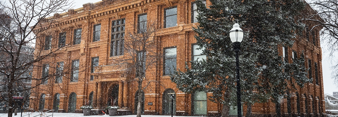 Jones Hall, a golden red-tone stone building, on a snowy winter day.