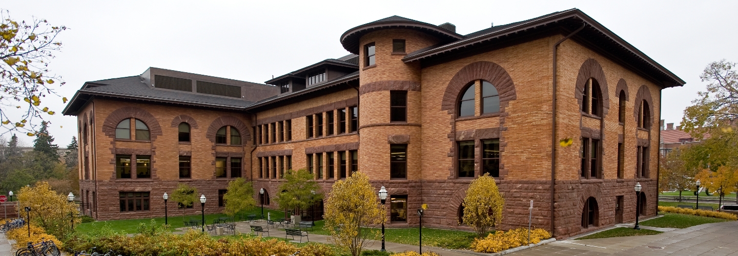 Exterior image of Nicholson hall, a brick building with arched windows and a turret, in the fall.