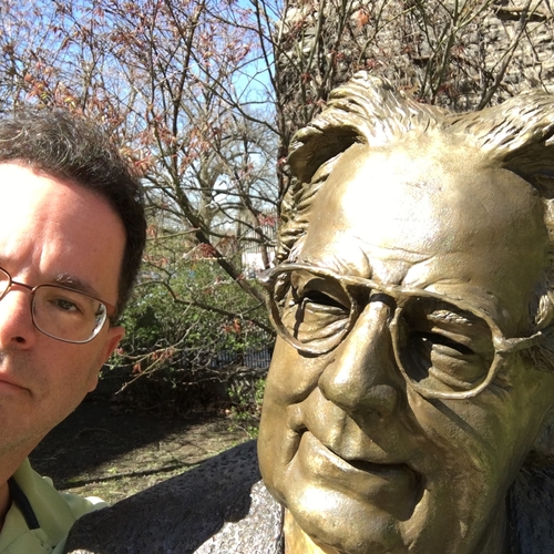 Picture of Andrew Scheil next to the statue of a famous literary critic