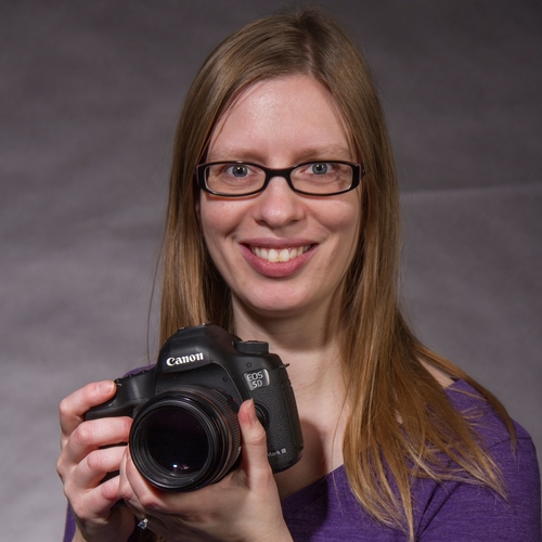 Caroline Houdek Solomon holding a camera and smiling.