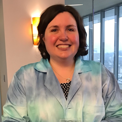 Smiling woman with short brown hair wearing a blue and green tie-dyed lab jacket