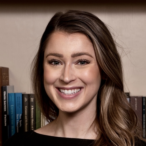 person smiling in front of bookshelf