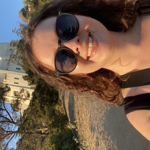 Smiling woman with dark curly hair and sunglasses at Griffith Observatory
