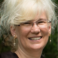 Headshot of Lynda Pavek smiling against dark background