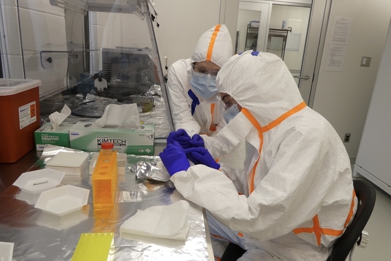 Photo of two people in protective equipment working in a lab
