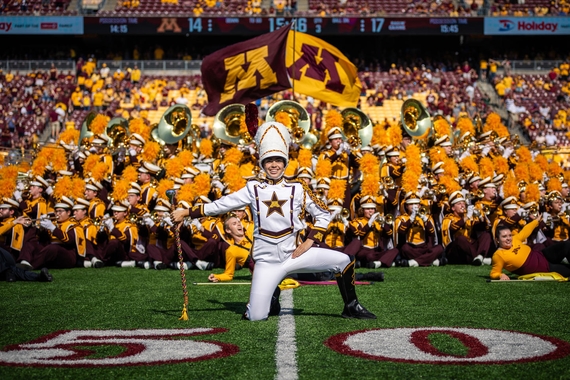 Ari Martin wears a white uniform and smiles during a marching band performance.