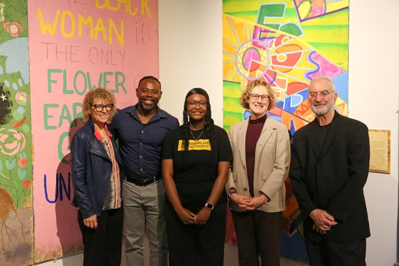 Faculty and staff in front of colorful murals in Nash Gallery